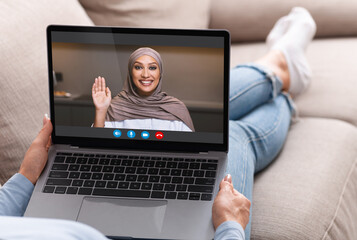Unrecognizable Lady Having Video Chat With Muslim Friend While Relaxing On Couch