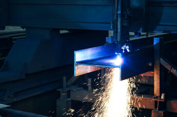 Drilling steel structure with sparks fly from drill machine in factory.