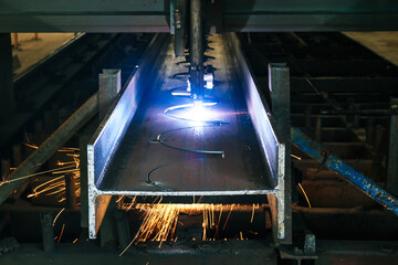Drilling steel structure with sparks fly from drill machine in cellular beam fabrication process...