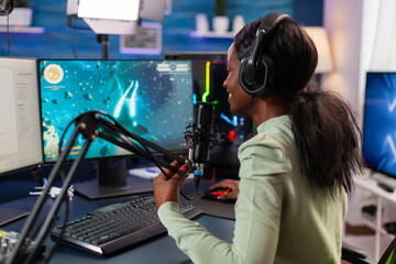 Naklejka premium African esports player talking with team during live space shooter stream competiton. Streaming viral video games for fun using headphones and keyboard for online championship.