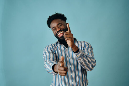 portrait of a black young african american man laughing with beard and mustache on a blue background