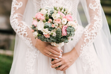 Obraz na płótnie Canvas Wedding bouquet in pastel colors in the hands of the bride of roses, eustoma, peonies, carnations and eucalyptus.