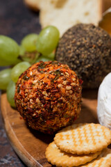 closeup of cheese, crackers and fruits, delicious snacks on wooden board, vertical