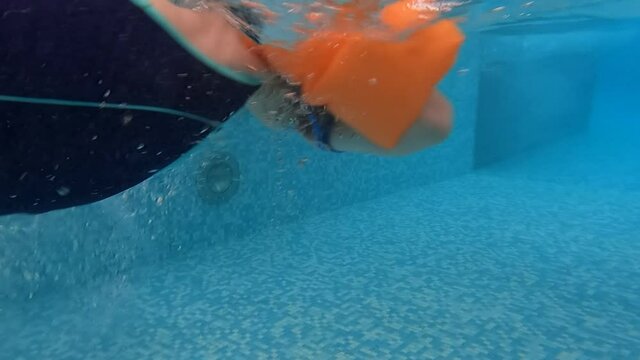 the girl in armbands dives into a swimming pool