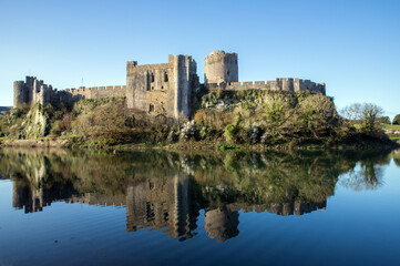 View of Pembroke castle in Pembrokeshire, Wales, UK with reflections on the water of the moat