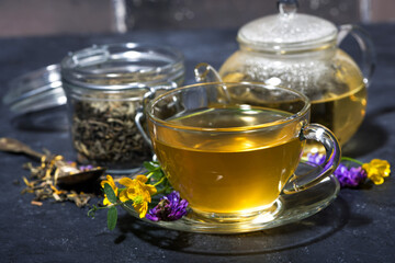 cup of tea with aromatic herbs on a dark background, closeup