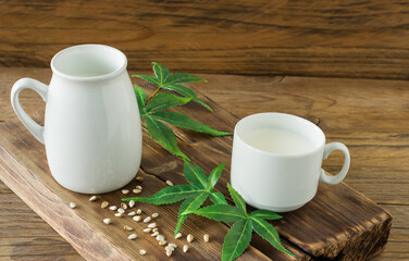 Cannabis herbal vegan gluten and lactose free milk and cannabis leaves on wooden table