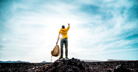 Successful man standing on the top of the mountain at sunset - Hiker with backpack extreme climbing...