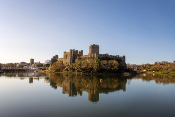 Fototapeta na wymiar View of Pembroke castle in Pembrokeshire, Wales, UK with reflections on the water of the moat