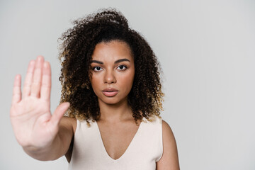 A portrait of concentrated woman showing stop gesture with palm to a camera in the studio