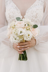 Wedding bouquet in pastel colors in the hands of the bride of roses, eustoma, peonies, carnations and eucalyptus.