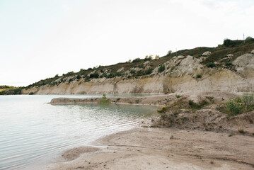 Shore with white clay close-up, turquoise azure water in pond, shallow lake with clear blue water,...