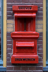 Obraz premium Old red postbox mounted in a brick wall of a house with the text BRIEVEN (letters) and DRUKWERKEN (press-work or printed matter) in Deventer, the Netherlands