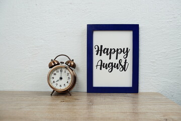 Happy August typography text and alarm clock on wooden table and white wall background - obrazy, fototapety, plakaty