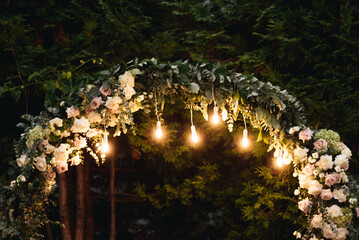 Beautiful wedding arch with retro lights decorated with night flowers, newlyweds ' night reception...
