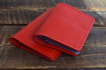 Business card holder and passport cover made of genuine red crust leather on a wooden table. Handmade leather goods