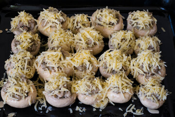 Stuffed mushrooms on a baking sheet. Champignons stuffed with onions, mushrooms and cheese, cooking.