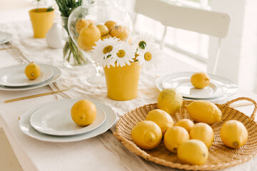 Beautifully served spring summer white table with lots of lemons and chamomile.