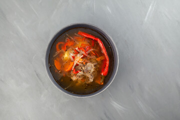 Shurpa or shorpa soup on grey background. Top view, copy space. Traditional uzbek dish with lamb, vegetables and spices