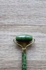 Jade face roller on wooden background. Flat lay.