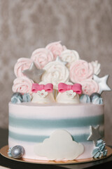 A beautiful cake made of natural ingredients with children's shoes in pink and gray colors for a girl's birthday or christening