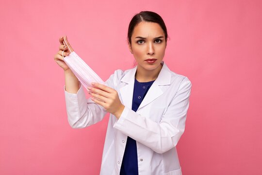 Sad young woman holds and wears a white medical mask to protect yourself from corona virus, cares for her health and safety, sticks to self-isolation. Concept of Covid-19