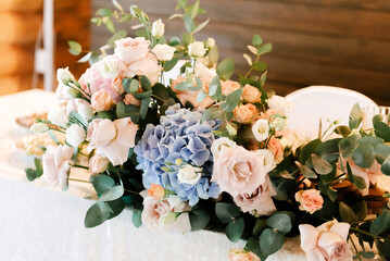 A beautiful composition of fresh flowers (rose, eucalyptus, hydrangea, eustoma) decorates the festive table