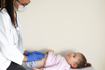 chubby little girl in pediatric examination by her doctor. Doctor examining the abdominal internal...