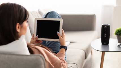 Back view of woman using tablet with empty mockup screen