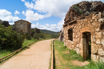 Hiker path in the natural landscapes of Cerro del Hierro with remains of old demolished houses in a mining area (Seville). Beautiful views in a natural environment on a sunny day with white clouds.