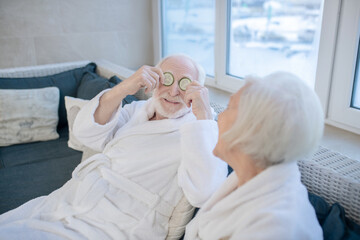 Mature couple in white robes relaxing in a spa center and feeling comfortable