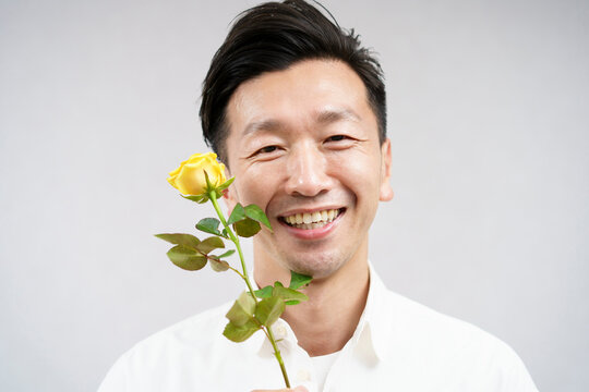 黄色い薔薇の花を持つ男性・父の日イメージ