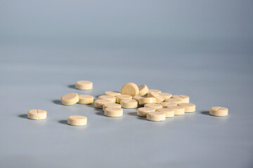 Scattering of round medicinal pills on gray background. Medicine concept of tablets, drugs, medicines and pills. Copy space. Selective focus.