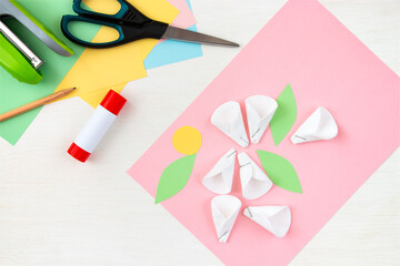 Cotton padded petals. Colored paper, stapler, scissors, scissors, pencil on a white table. Children's crafts for mother's day. Step-by-step instruction. Step 5.