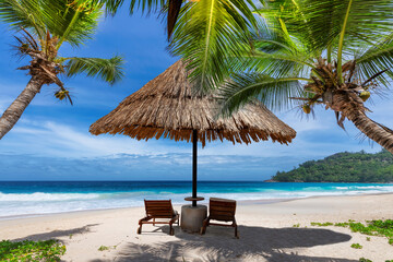 Tropical Sunny beach with coco palms and sun umbrella, beach sunbeds, turquoise sea in tropical...