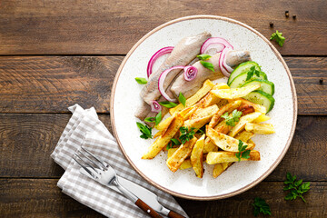 Pickled herring fillet with onion and fried potato on plate