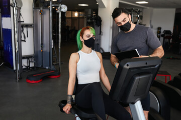 Personal trainer and sporty woman exercising wearing face masks during pandemic