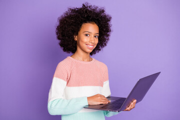 Obraz na płótnie Canvas Portrait of optimistic curly hairdo girl type laptop wear white sweater isolated on violet background