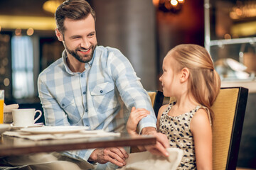 Dad having breakfast with his daughter and looking happy
