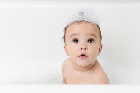 Cute baby girl in bubble bath with shampoo on head