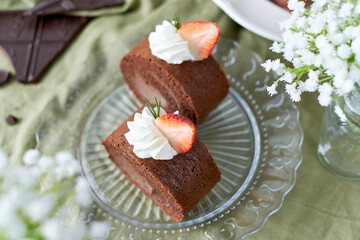 Chocolate Swiss Roll Cake with Chocolate cream filling and Strawberry set on cafe table.