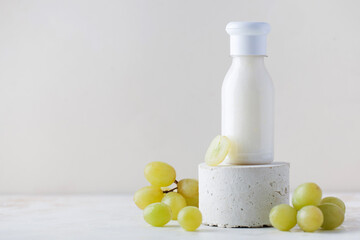 Grape cosmetics. A tube of cream, lotion for the skin of the face and body with grape extract on a pedestal. Copy space.