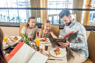 Cute family sitting at the table and cchoosing the meal