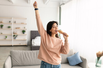 Young woman dancing and singing in hairbrush
