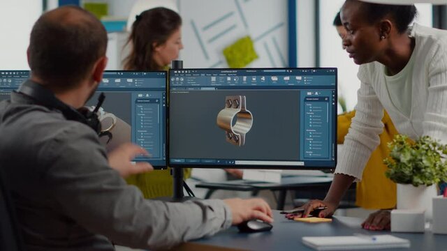 Diverse team discussing about industrial project using dual monitors setup to desing 3D gears and metalic clamp in CAD software. Industrial engineer and african manager working in creative office