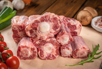 Beef Oxtail Meat on kitchen table with vegetables, close up