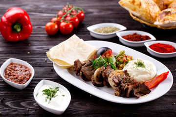 Assorted Middle Eastern and arabic dishes on a dark rustic background. Hummus, tabbouleh, pita, meat kebab, falafel, baklava. Halal food. Top view. Turkish foods, Turkish pizza, Turkish breakfast