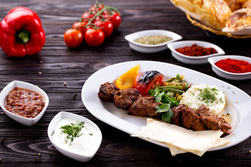 Assorted Middle Eastern and arabic dishes on a dark rustic background. Hummus, tabbouleh, pita, meat kebab, falafel, baklava. Halal food. Top view. Turkish foods, Turkish pizza, Turkish breakfast