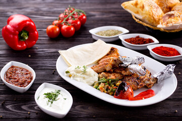 Assorted Middle Eastern and arabic dishes on a dark rustic background. Hummus, tabbouleh, pita, meat kebab, falafel, baklava. Halal food. Top view. Turkish foods, Turkish pizza, Turkish breakfast