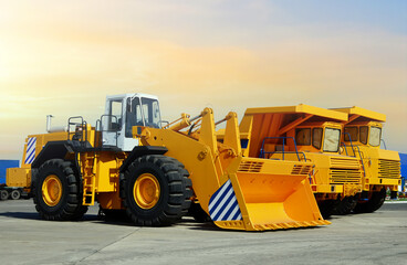 Obraz na płótnie Canvas Wheel loader and mining truck. Heavy construction machinery and mining equipment. Front-end loader or all-wheel bulldozer and dump trucks